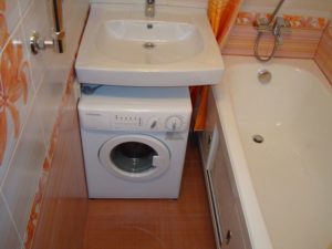 Washing machine under the sink in the bathroom